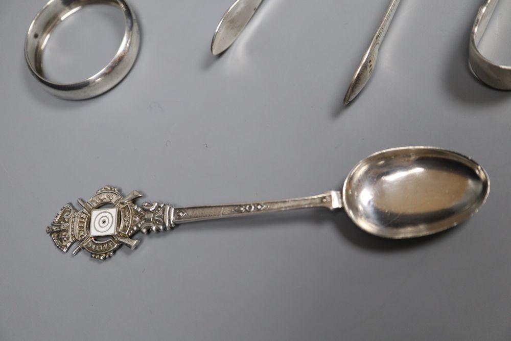 Small silver including a pair of Georgian sugar tongs, cased pepperettes, two napkin rings, spoon, tongs and wine label.